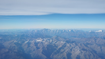 Flying over the European Alps during fall season. Landscape at the Mont Blanc and the glaciers. Aerial view from the airplane window