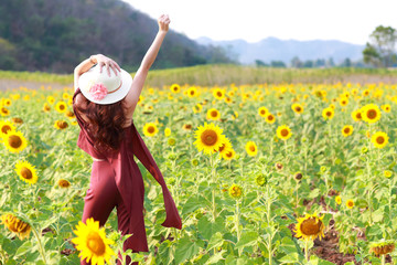 Portrait of beautiful woman having a happy time and enjoying among sunflower field in nature