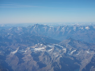 Flying over the European Alps during fall season. Landscape at the Mont Blanc and the glaciers. Aerial view from the airplane window