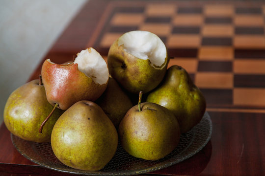 Green pears lie on plate next to chessboard