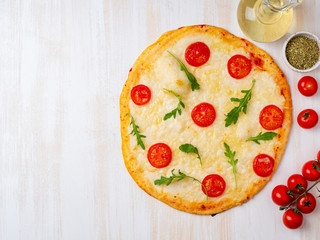 hot homemade Italian pizza margherita with mozzarella and tomatoes on white wooden table, top view