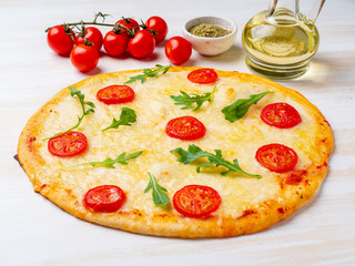 hot homemade Italian pizza margherita with mozzarella and tomatoes on white wooden table, side view