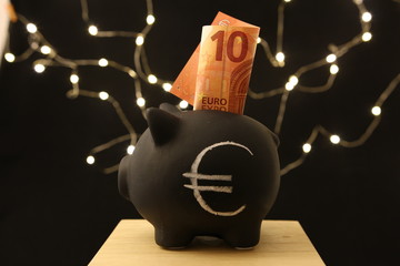 Saving money - black piggy banks with 10 EURO on black background with lightings - obrazy, fototapety, plakaty