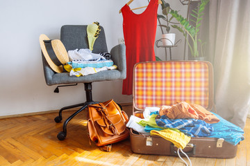 overloaded valise with clothes. prepared garment on chair. travel concept