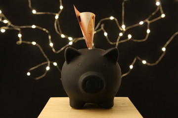 Saving money - black piggy banks with 10 EURO on black background with lightings © Cezzar