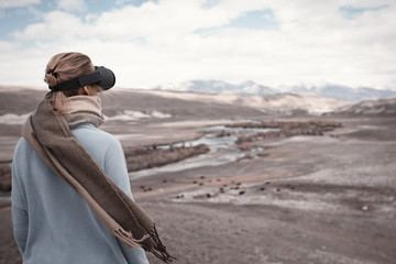 Woman travels in virtual reality. Wild nature at background.