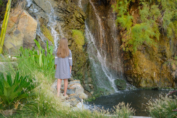 Fototapeta na wymiar kid girl stands at a very beautiful waterfall