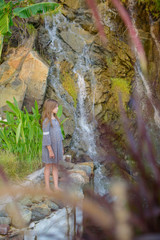 kid girl stands at a very beautiful waterfall