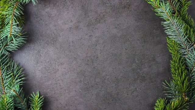 Christmas tree pine branches rotating on dark texture surface. Close up.