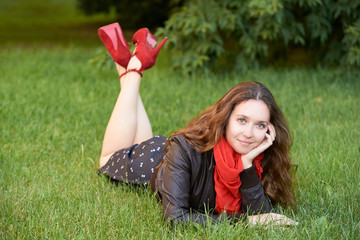 Young girl with red scarf lying on green grass