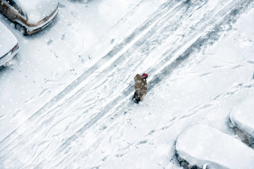 Elevated view of people walking during snow on frozen street with covered parked cars - Powered by Adobe