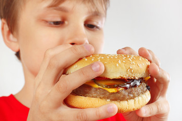 Young boy eat the hamburger on a white background close up