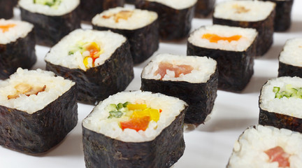 Assorted asian sushi with salmon, tuna, eel and vegetables on a white background close up.