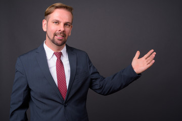 Blond bearded businessman with goatee against gray background