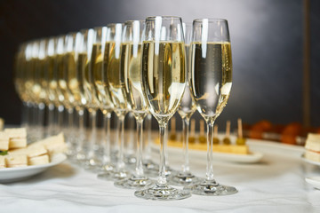 rows of champagne and sparkling wine glasses at banquet night time party new year corporate party concept