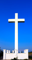White and stone to cross on hill. Blue sky