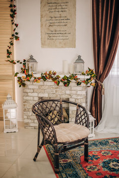 Wicker stylish chair near the fireplace in the autumn interior. Background for postcard