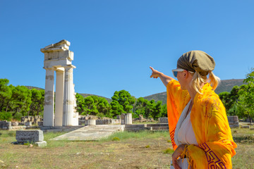 Greek dressed woman in indicates the ruins of Temple of Asklepieion, Epidaurus, Peloponnese, Greece. The Sanctuary of Asclepius is a famous heritage site.Mediterranean travel and tourism concept