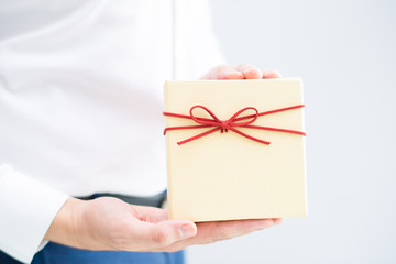 Closeup of person holding gift box. Man showing gift box. Gift concept. Isolated cropped view on grey background.