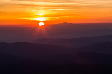 Beautiful sunset with sun coming down behind various layers of mountains