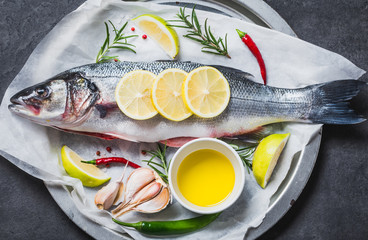 Fresh fish sea bass and ingredients for cooking. Raw fish sea bass with spices and herbs on black...