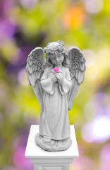 cute girl angel statue holding flower on her hand  with  colorful background at garden