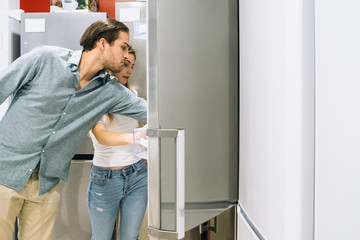 Fototapeta na wymiar Young man and woman choosing a fridge