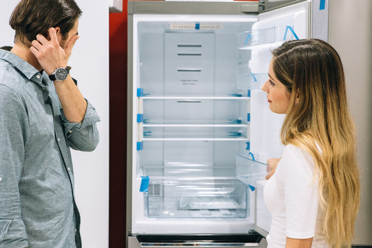 Young woman and man choose a fridge in a store