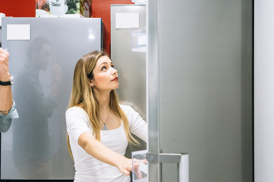 Young woman chooses a fridge in an appliance shop