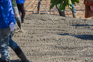 Workers using a wooden spatula for cement after Pouring ready-mixed concrete on steel reinforcement...