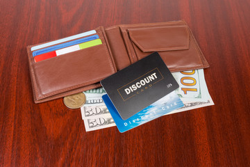 Plastic discount cards on open brown leather wallet and money