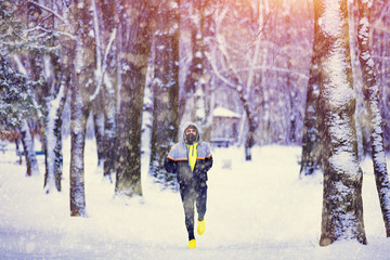 Man jogging in snowy park and cold weather.