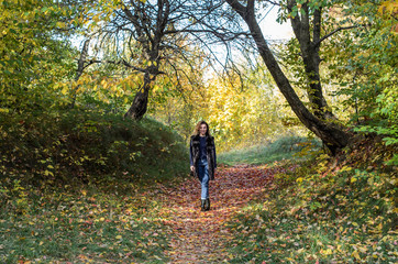 Obraz premium Young beautiful girl with long hair walks in the autumn forest