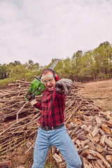 Lumberjack with chainsaw and pile of cut woods.