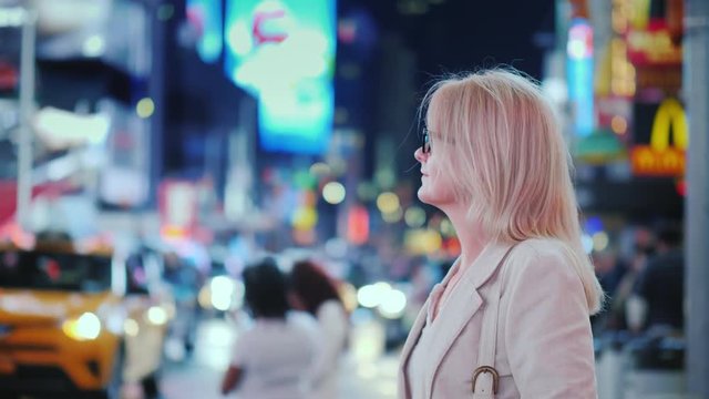 Attractive woman admiring the lights of the famous Time Square in New York, yellow cabs passing by - the symbol of the city