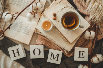 Still life details in home interior of living room and the inscription HOME. Books and cup of tea with cone and cotton. Read. Rest