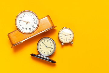 Three different Wooden retro alarm clock on bright yellow minimalistic background top view Flat Lay with copy space. The concept of time, morning, education.