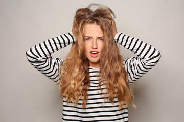 Portrait of beautiful young woman suffering from headache on light background