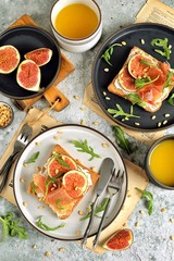 Healthy sandwiches from rye bread with soft cheese, jamon, figs, arugula and pine nuts.