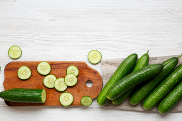 Fresh raw organic green cucumbers, top view. Flat lay, from above, overhead. White wooden background. Space for text.