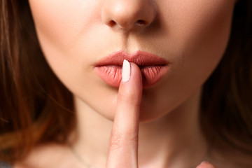 Female put finger to closed red lips asking keep silent