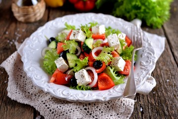 Classic Greek salad from tomatoes, cucumbers, red pepper, onion with olives, oregano and feta cheese.