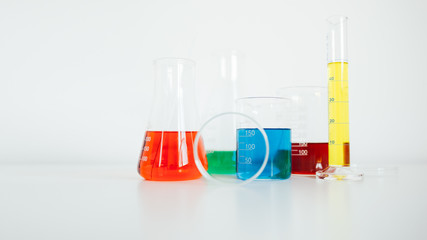 Laboratory equipment. Laboratory glassware with colorful liquids on white table