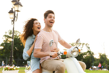 Portrait of romantic couple man and woman, riding on motorbike together through city street