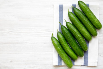 Fresh organic green cucumbers on white wooden table, overhead view. Flat lay, from above, top view. Copy space.