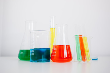 Laboratory glassware with colorful liquids on white table