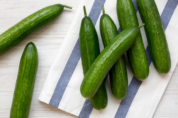Fresh organic green cucumbers on white wooden surface, overhead view. Flat lay, from above, top view.
