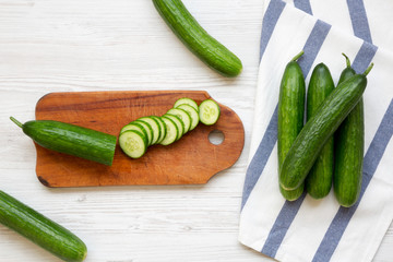 Fresh raw green cucumbers, overhead view. Flat lay, from above, top view. White wooden background.