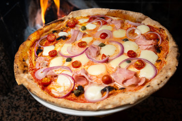 Pizza con prosciutto cotto, cipolla, mozzarella, sugo, pomodorini e latte vaccino fuso 