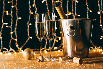 two glasses and champagne bottle in bucket on garland light background, christmas concept © LIGHTFIELD STUDIOS